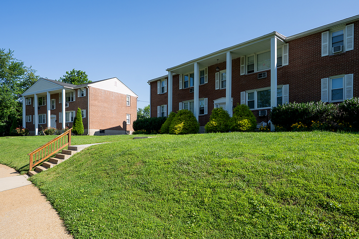 Charming brick apartment buildings set in a lush green landscape, offering a peaceful and inviting community atmosphere.