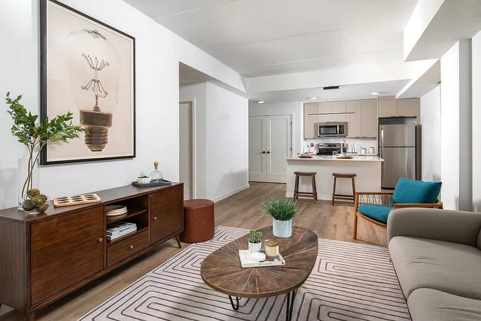 Chic and contemporary open-concept living space featuring a cozy sitting area, stylish kitchen with bar stools, and elegant decor elements.
