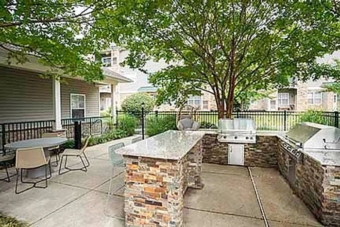 Chic outdoor patio area with lush greenery, modern lounge furniture, and poolside views at a luxurious apartment complex.