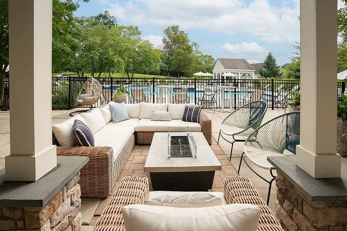 Chic outdoor patio area with lush greenery, modern lounge furniture, and poolside views at a luxurious apartment complex.