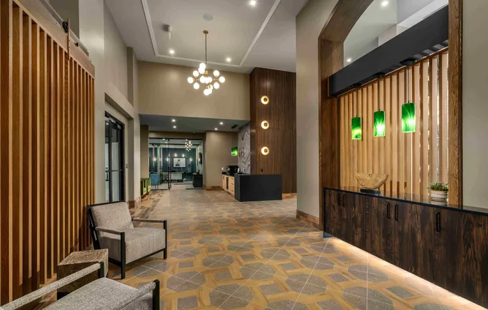 Elegant apartment lobby with modern lighting, sleek wooden accents, and stylish seating, creating a welcoming and sophisticated atmosphere.