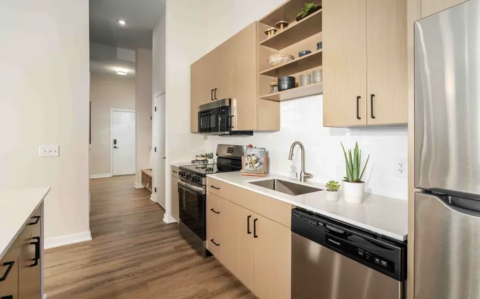 Modern kitchen with sleek stainless steel appliances, elegant wooden cabinetry, and chic white countertops, creating a stylish and functional cooking space.