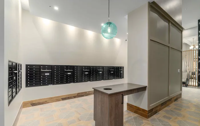 Modern mailroom with sleek black mailboxes and a stylish wooden counter, featuring elegant lighting and contemporary design.