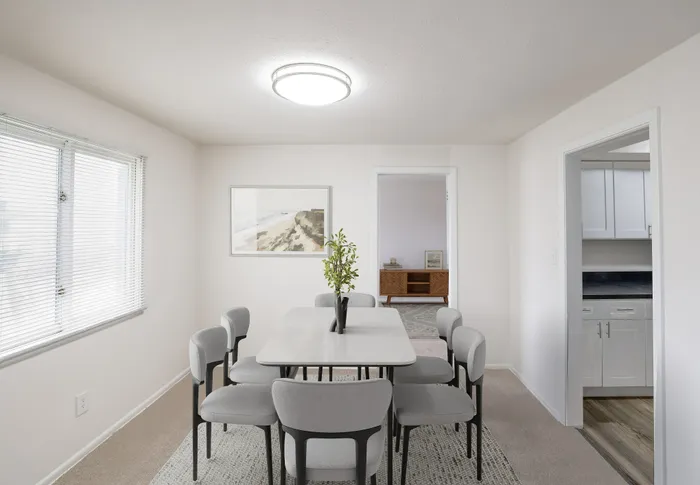 Bright dining area with modern table and chairs, featuring a chic art piece and natural light from a large window.