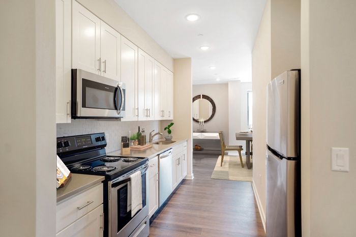 Sleek modern kitchen with stainless steel appliances, ample cabinetry, and bright ambient lighting opening to a cozy dining area.