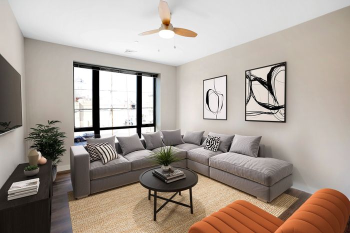 Contemporary living room with stylish gray sectional, modern art decor, and large windows offering abundant natural light.