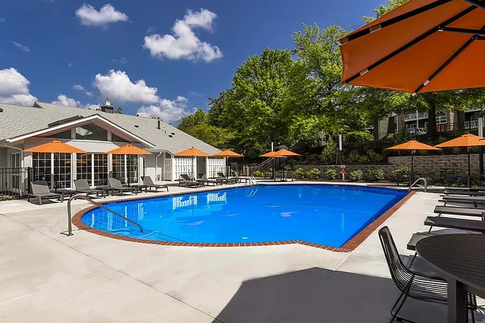 Inviting outdoor pool area with vibrant orange umbrellas and comfortable lounge chairs, perfect for relaxation and enjoying sunny days.
