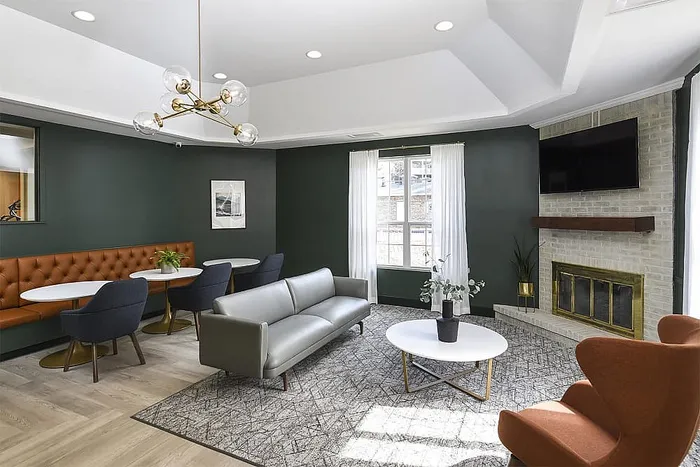 Chic living area with elegant green walls, modern seating, stylish lighting, and a cozy fireplace.