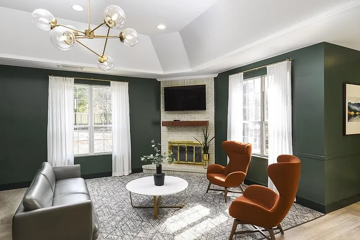 Elegant living room with modern chandelier, cozy fireplace, and stylish armchairs featuring a warm, inviting ambiance.