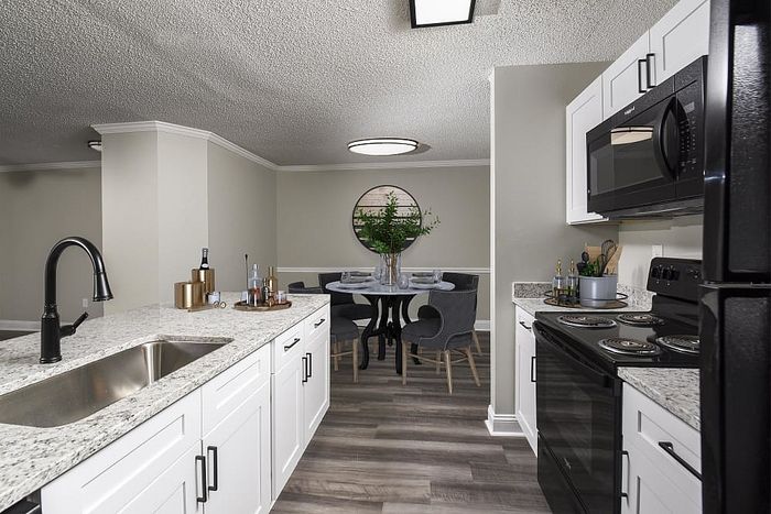 Modern kitchen with sleek granite countertops leading to a chic dining area, featuring stylish lighting and contemporary decor.