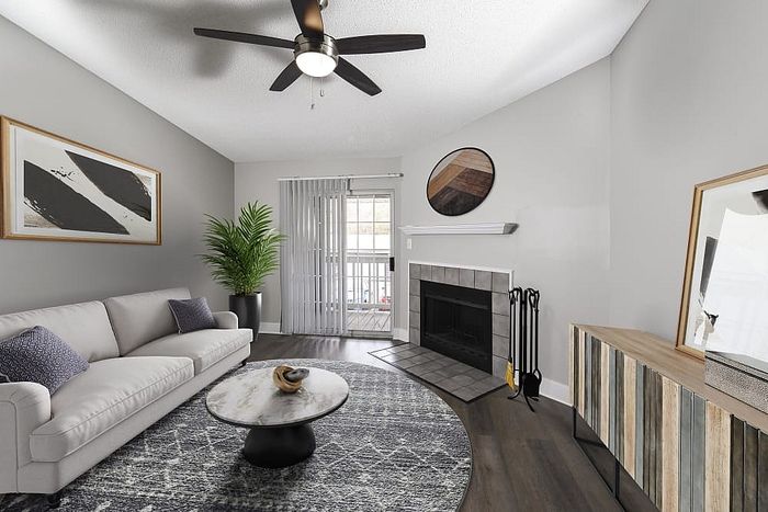 Modern living room with chic decor, featuring a cozy fireplace, stylish coffee table, and spacious sofa. Enjoy natural light streaming through large glass doors, complemented by a sleek ceiling fan and elegant artwork.