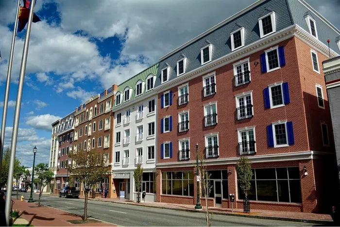 Charming multi-story brick apartment building with colorful shutters, showcasing classic architecture under a vibrant blue sky.