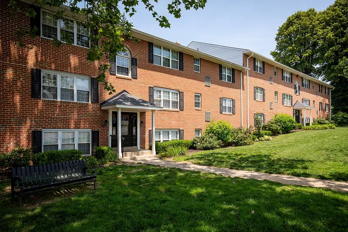 Charming brick apartment building with lush green landscaping and inviting pathways.
