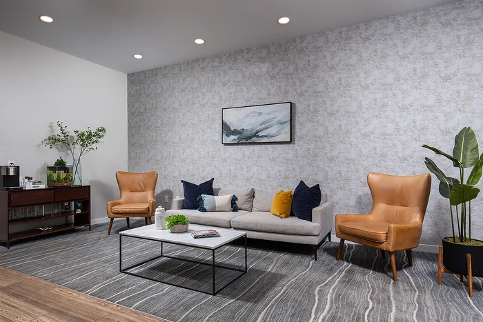 Sophisticated living room with modern design featuring cozy beige sofa, stylish leather armchairs, and elegant decor against a subtle patterned wall.