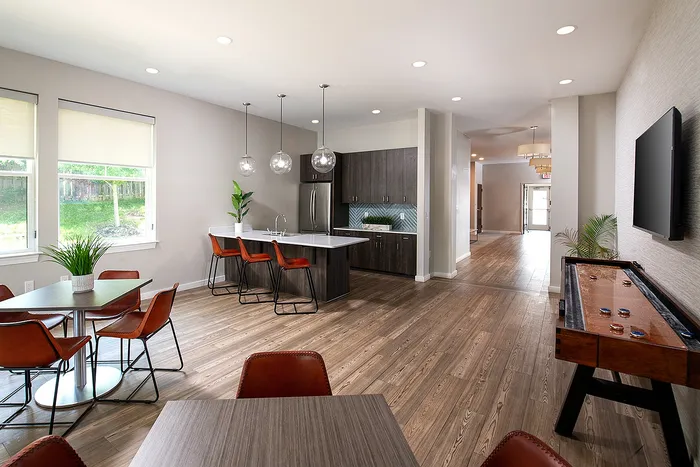 Modern open-concept apartment featuring a stylish kitchen with island, cozy dining area, and sleek wooden floors, perfect for entertaining.