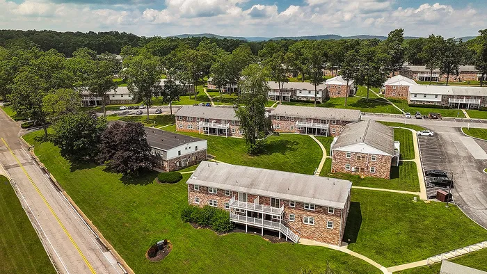 Charming aerial view of a picturesque apartment community surrounded by lush greenery and scenic landscapes.
