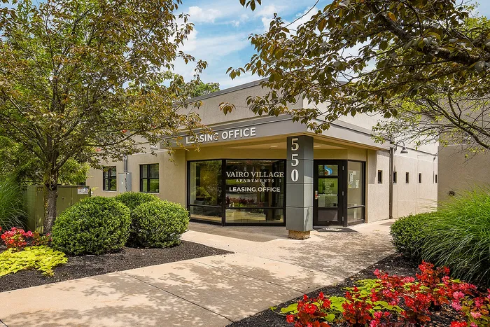 Welcoming entrance to Vairo Village Apartments leasing office surrounded by vibrant landscaping and modern architecture.