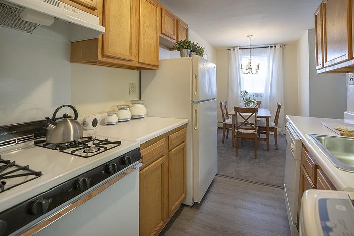 Charming kitchen and dining area with wooden cabinets, modern appliances, and a cozy dining table near a bright window.