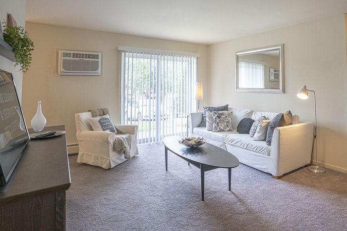 Inviting living room with abundant natural light, modern decor, and cozy seating area enhanced by a large window with blinds.