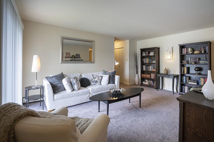 Inviting and stylish living room featuring a cozy white sofa, elegant bookshelf, and modern decor with soft lighting.