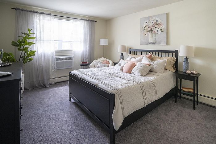 Bright and cozy bedroom with elegant decor, featuring a comfortable bed, stylish side tables, and a large window draped with sheer curtains.