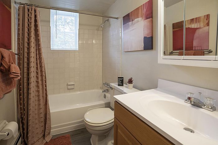 Inviting bathroom featuring elegant tiling, a cozy tub with a soft blush shower curtain, and modern fixtures under warm lighting.