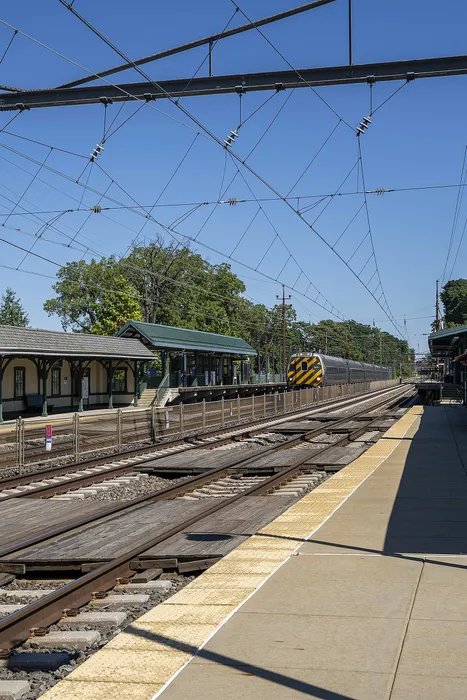 Charming train station platform with scenic views, surrounded by lush trees and clear blue skies.