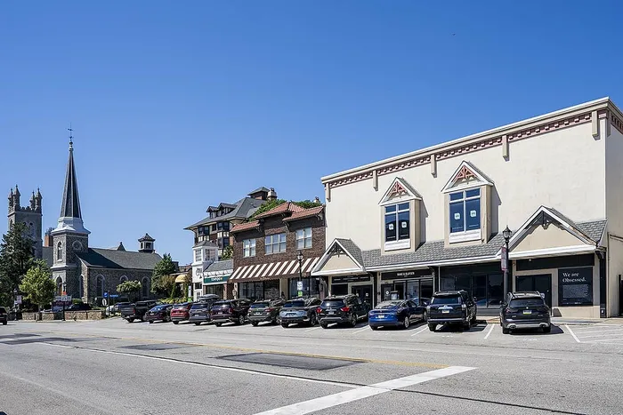 Charming downtown scene with historic church, retail shops, and ample parking under a clear blue sky.