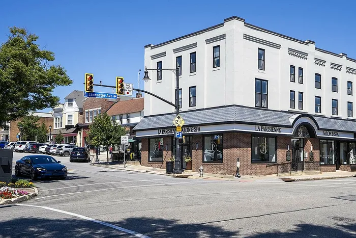 Charming corner building with modern architecture, housing La Parisienne Salon & Spa on a sunny street corner with nearby parking.