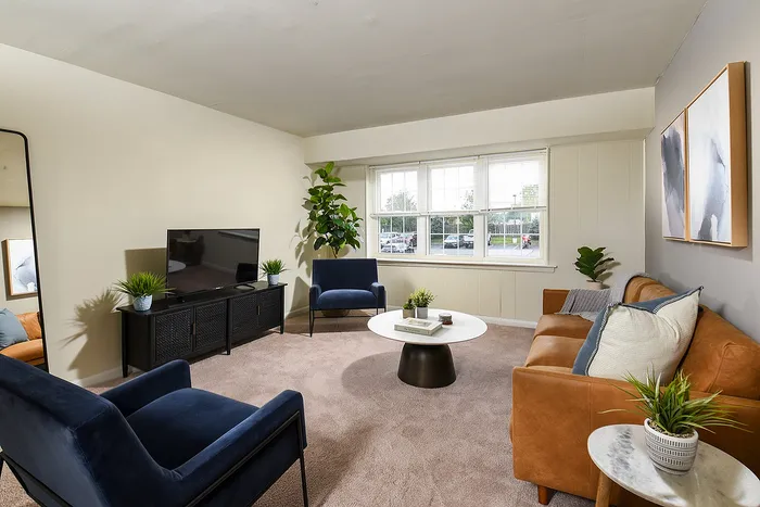 Bright and inviting living room featuring a stylish leather couch, modern decor, and abundant natural light through large windows.