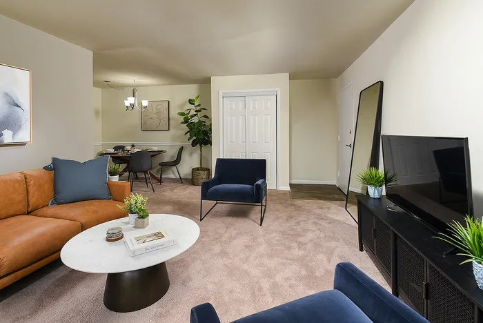 Inviting living room with a cozy brown leather sofa, modern blue armchair, and stylish decor leading to a chic dining area.