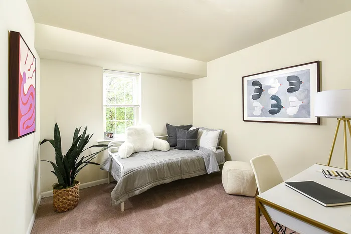 Bright and cozy bedroom featuring a stylish daybed with plush pillows, modern artwork, and abundant natural light.