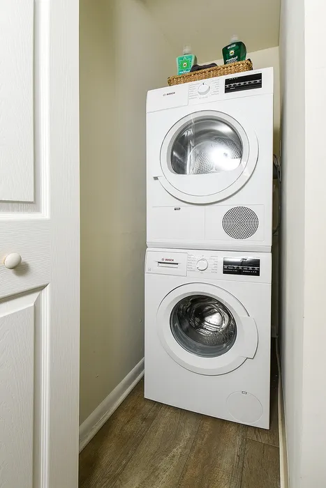 Efficient laundry nook featuring a sleek, stacked washer and dryer with cleaning supplies, maximizing apartment space.