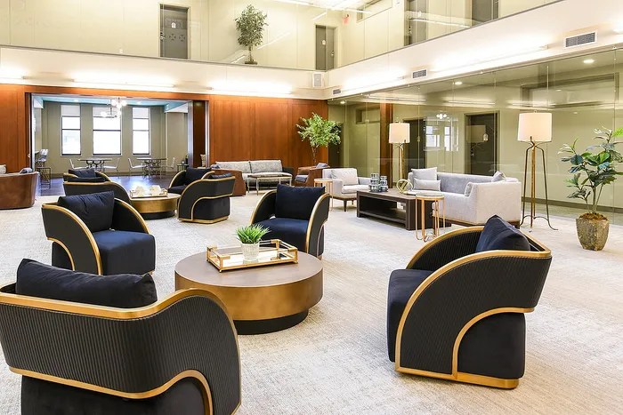 Luxurious lobby featuring modern black and gold seating, elegant decor, and abundant natural light in a sophisticated apartment setting.