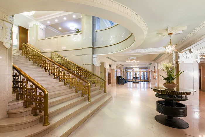 Grand apartment lobby with elegant staircase, ornate lighting, and luxurious design elements.