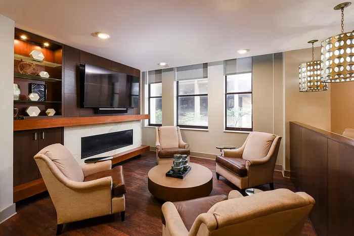 Elegant lounge area with plush armchairs, a modern fireplace, and a stylish TV setup against a beautifully crafted wooden accent wall.
