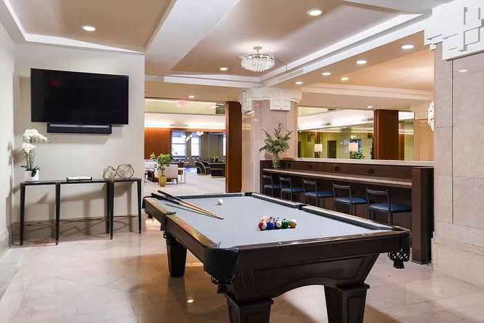 Luxurious recreation room featuring a sleek billiards table, modern decor with a mounted TV, and elegant seating area, perfect for entertaining.