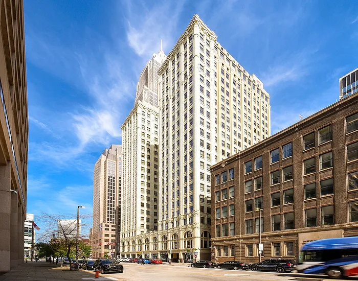 Stunning cityscape view featuring a majestic high-rise building framed by clear blue skies, showcasing prime downtown living opportunities.