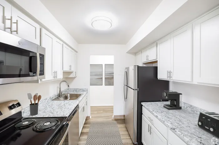 Modern kitchen with sleek stainless steel appliances, elegant white cabinetry, and chic granite countertops.