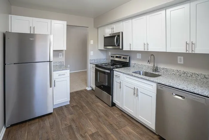 Modern kitchen with sleek stainless steel appliances, white cabinetry, and elegant granite countertops.