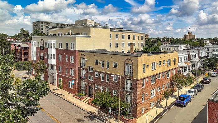 Charming urban apartment complex with classic brick exterior, surrounded by tree-lined streets and vibrant cityscape.