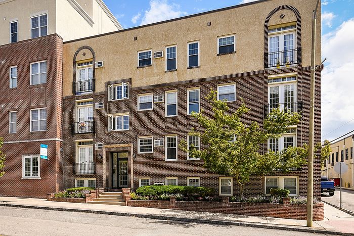 Charming multi-story brick apartment building with elegant architectural details and lush greenery, offering urban living in a vibrant neighborhood.