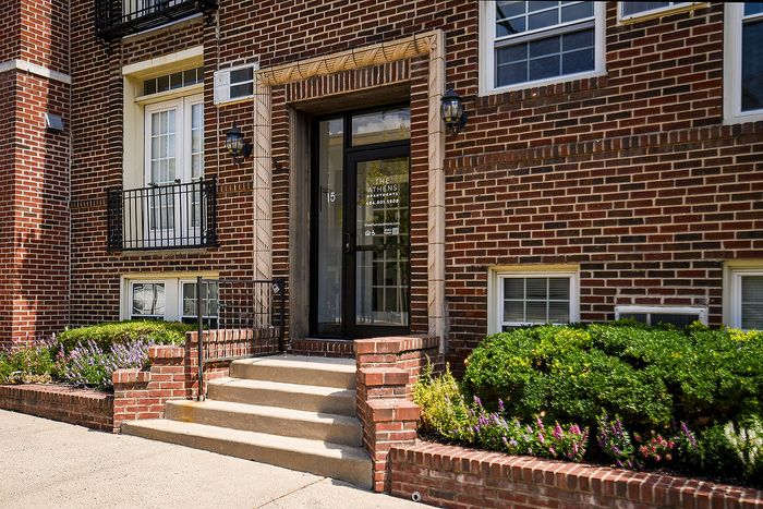 Charming brick apartment entrance with elegant landscaping, showcasing curb appeal and inviting ambiance.