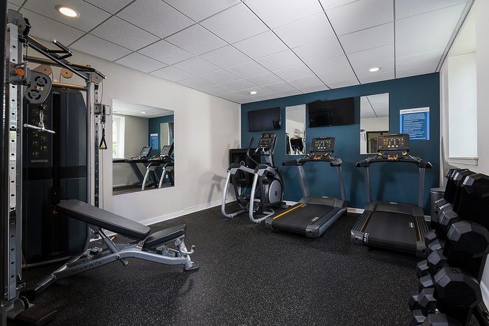 Modern fitness center with state-of-the-art equipment including treadmills, an elliptical machine, weight bench, and free weights, designed for a complete workout experience.