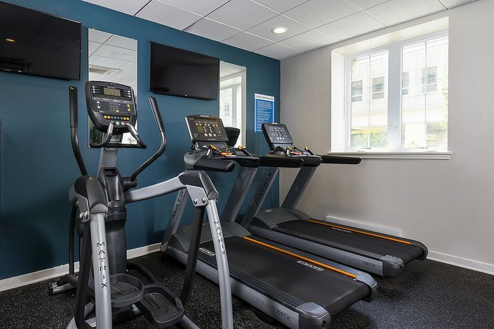 Modern fitness room with advanced exercise equipment, including treadmills and an elliptical, creating an inviting workout space.