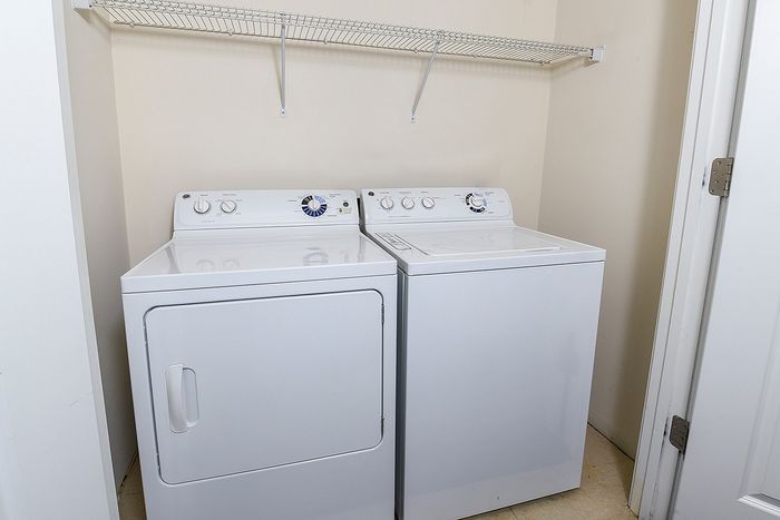Modern laundry area featuring a washer and dryer set with a convenient overhead storage shelf.