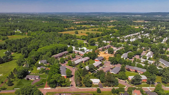 Scenic aerial view of a tranquil suburban neighborhood surrounded by lush greenery and open spaces, offering a perfect blend of nature and community living.