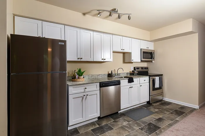 Modern kitchen with sleek stainless steel appliances, elegant white cabinetry, and stylish granite countertops, showcasing a contemporary and inviting atmosphere.