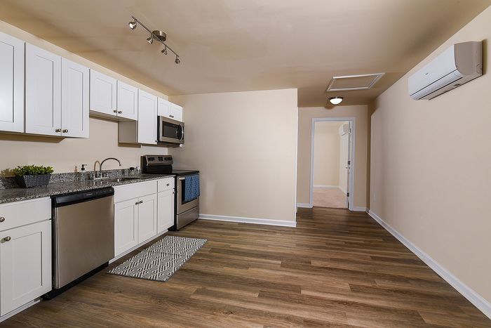 Modern kitchen with stainless steel appliances, elegant cabinetry, and hardwood floors leading to a cozy hallway.