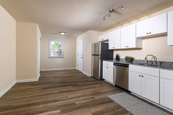 Modern kitchen with sleek white cabinetry, stainless steel appliances, and elegant wood flooring, perfect for culinary enthusiasts.